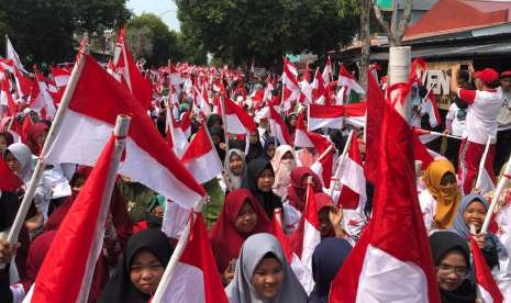 Aksi 1.945 perempuan mengibarkan Bendera Merah Putih setelah sebelumnya dijahit sendiri, Minggu (30/9). Aksi dalam rangkaian Kirab Satu Negeri tersebut diganjar rekor MURI.