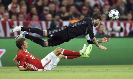 Aksi saling berebut bola antara pemain Bayern Muenchen, Thomas Mueller (bawah) dengan pemain Real Madrid, Sergio Ramos saat laga perempat final Liga Champions di Munich, Jerman, Rabu (12/4).