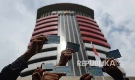 Aktivis Koalisi Masyarakat Sipil menunjukan Kartu Tanda Penduduk (KTP) Elektronik saat melakukan aksi di depan Gedung Komisi Pemberantasan Korupsi (KPK), Jakarta, Ahad (12/3).