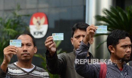 Aktivis Koalisi Masyarakat Sipil menunjukan Kartu Tanda Penduduk (KTP) Elektronik saat melakukan aksi di depan Gedung Komisi Pemberantasan Korupsi (KPK), Jakarta, Ahad (12/3).