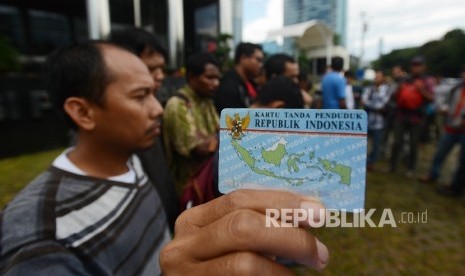 Aktivis Koalisi Masyarakat Sipil menunjukan Kartu Tanda Penduduk (KTP) Elektronik saat melakukan aksi di depan Gedung Komisi Pemberantasan Korupsi (KPK), Jakarta, Ahad (12/3).