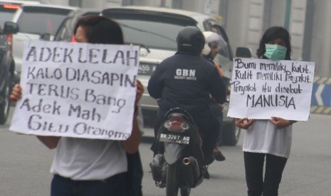 Aktivis lingkungan dari Komunitas Satria Hijau membentangkan poster saat menggelar aksi menolak kabut asap di Medan, Sumatera Utara, Jumat (23/10). 