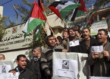 Aktivis Palestina mengibarkan bendera Palestina sambil memegang kertas suara pemilu saat menggelar demonstrasi menyerukan pemilu dan bergabungnya Fatah dan Hamas di Gaza City, Palestina, Rabu (25/1). 