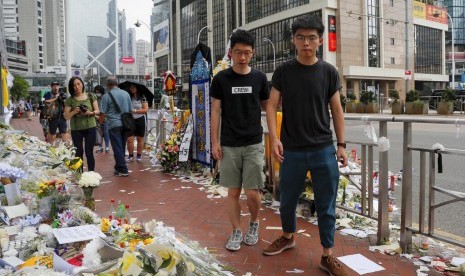 Aktivis prodemokrasi Hong Kong Joshua Wong (kanan) dengan ditemani Nathan Law memberi penghormatan pada seorang demonstran yang jatuh dan meninggal saat protes menentang RUU ekstradisi di Hong Kong, Senin (17/6).