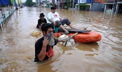 Aktivitas warga di Jalan Abdullah Syafei yang tergenang banjir akibat meluapnya Kali Ciliwung di Kampung Melayu, Jakarta, Sabtu (18/1). (Republika/Prayogi)