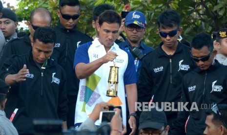 Aktor Hamish Daud (kedua kiri) membawa api obor Asian Games 2018 saat tiba di objek wisata Tanah Lot, Kabupaten Tabanan, Bali, Senin (23/7).