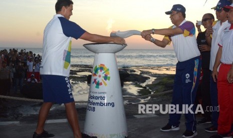 Celebrity Hamish Daud (left) handed over Asian Games 2018 torch to Tabanan District Secretary, Nyoman Wirna Ariwangsa at Tanah Lot, Tabanan, Bali, Monday (July 23). 