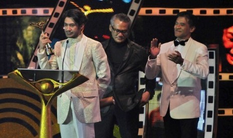 Aktor Reza Rahadian (kiri) memperlihatkan Piala Citra untuk kategori pemeran utama pria terbaik dalam film Habibie & Ainun, pada Malam Penganugerahan Festival Film Indonesia (FFI) 2013 di Marina Convention Centre (MCC) Semarang, Jateng, Sabtu (7/12) malam