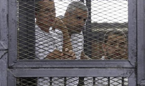 Al Jazeera journalists (left to right) Peter Greste, Mohammed Fahmy and Baher Mohamed stand behind bars at a court in Cairo June 1, 2014.