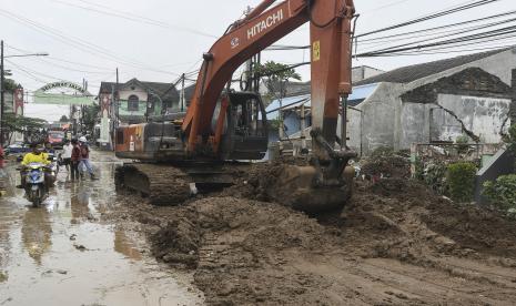 Alat berat eskavator membersihkan tanah yang menggangu pengguna jalan usai banjir di Pondok Gede Permai, Bekasi, Jawa Barat, Kamis (17/2/2022). Menurut data BPBD 11 titik di 4 Kecamatan yaitu Jatiasih, Bekasi Timur, Bekasi Selatan dan Bekasi Utara tergenang banjir disertai lumpur akibat luapan kali Bekasi.