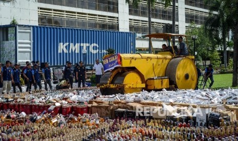 Alat berat memusnahkan ribuan minuman keras dan rokok hasil sitaan bea cukai di halaman gedung Bea Cukai, Jakarta Timur, Jumat (23/12). 