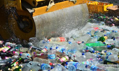 Alat berat menggilas botol miras saat pemusnahan.