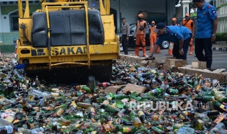 Alat berat menggilas puluhan ribu botol minuman keras (miras) saat pemusnahan di halaman Polres Metro Jakarta Selatan, Kamis (2/6)