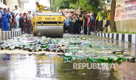 Alat berat menggilas sedikitnya 1.900 botol minuman keras hasil Operasi Pekat Lodaya menjelang Ramadhan, di halaman Polres Kota Tasikmalaya, Kamis (2/6). (Republika/Fuji E Permana)