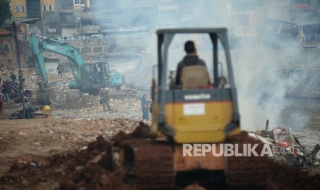 Alat berat meratakan tanah sebagai tahap awal normalisasi di Bantaran kali Ciliwung, Bukit Duri, Jakarta, Selasa (4/10).