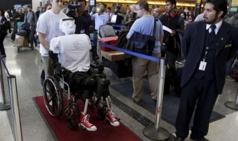 Alexander Herzog, a doctoral student at Max Planck Society, pushes 'Athena', the first 'humanoid' robot to fly as a passenger, as they arrive at Los Angeles International Airport, California December 15, 2014. 