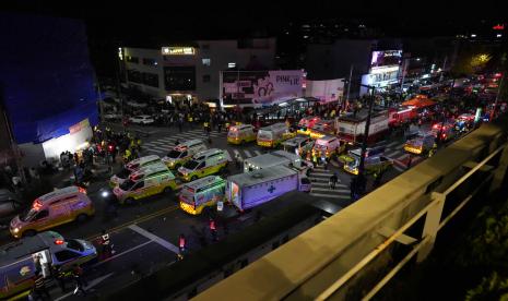 Ambulans dan petugas penyelamat tiba di jalan dekat tempat terjadinya lonjakan massa di Seoul, Korea Selatan, Minggu, 30 Oktober 2022. Saksi mata mengatakan pemandangan mengerikan itu semakin intensif ketika orang-orang melakukan CPR pada orang yang sekarat dan membawa tubuh lemas ke ambulans, sementara musik dansa berdenyut dari klub norak menyala dalam neon terang. Yang lain berusaha mati-matian untuk menarik keluar mereka yang terjebak di bawah himpitan orang, tetapi gagal karena terlalu banyak orang yang jatuh di atas mereka.