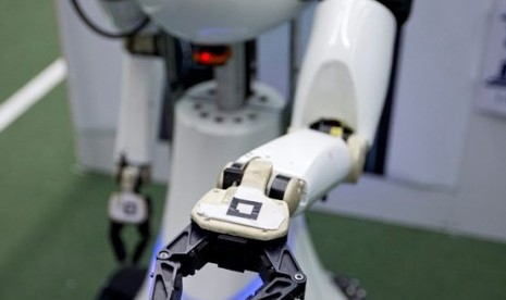 Amigo, a white robot the size of a person, uses information gathered by other robots to move towards a table to pick up a carton of milk and deliver it to an imaginary patient in a mock hospital room at the Technical University of Eindhoven, Netherlands, W