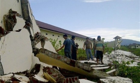 An Acehnese man makes his way under the collapsed roof of a building after it was destroyed by an earthquake in Ketol, Central Aceh, Indonesia, early Wednesday, July 3, 2013. 