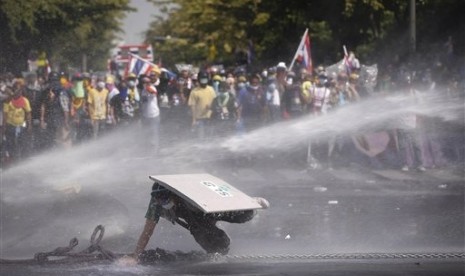 An Anti-government protester falls as he is hit by water cannon by police in Bangkok, Thailand, Monday, Dec 2, 2013. 