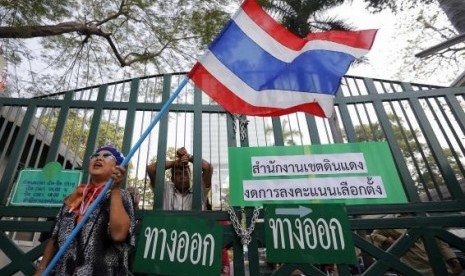 An anti-government protester waves a flag in front of the locked gates of a polling station her group had forced to close in Bangkok January 26, 2014. 