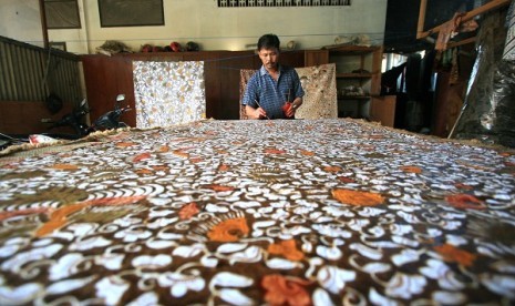 An artisan gives a finishing color of a piece of batik pattern in Paoman, Indramayu, West Java. (illustration)