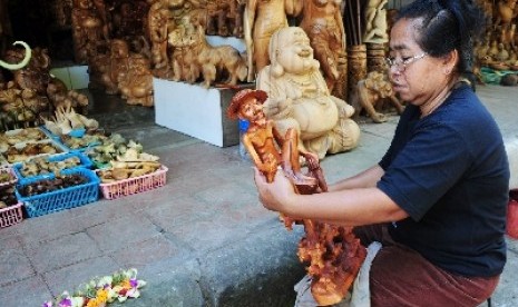 An artisan polish balinese wooden sculpture in a workshop in Bali. (illustration)