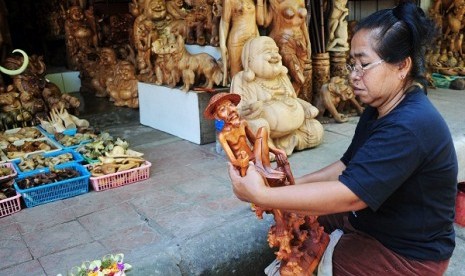 An artisan smoothens the wooden statue using a piece of sandpaper in Ubud, Bali. (iilustration)