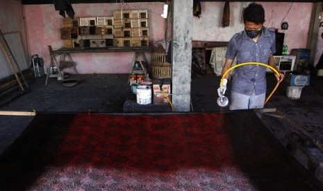 An artisan sprays some colors to a piece if batik print in Pekalongan, Central Java. (illustration)