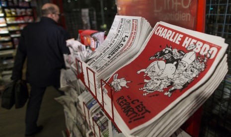 Seorang penumpang kereta komuter berjalan di depan rak yang memajang tabloid Charlie Hebdo di stasiun Gare du Nord di Paris. Empat warga Pakistan menuntut dan menahan empat orang Pakistan yang dicurigai terkait dengan serangan di luar bekas kantor Charlie Hebdo. Ilustrasi.