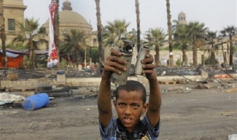 An Egyptian child displays empty tear gas canisters among the debris of a protest camp in Nahda Square, near Cairo University in Giza, Cairo, Egypt, Thursday, Aug. 15, 2013. (file photo)