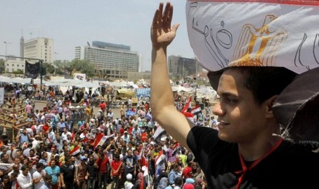 An Egyptian protester covers his head by a national flag during a demonstration against President Mohammad Mursi in Tahrir Square in Cairo, Monday, July 1, 2013.