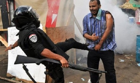 An Egyptian security force kicks a supporter of ousted President Mohammed Mursi as they clear a sit-in camp set up near Cairo University in Cairo's Giza district, Wednesday, Aug. 14, 2013. 