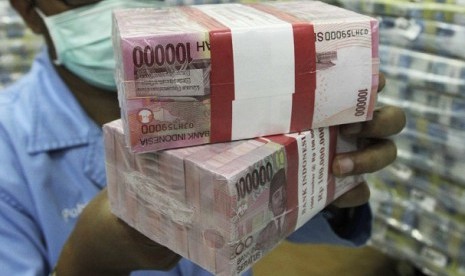 An employee of a bank holds bundles of Indonesian rupiah banknotes at Bank Mandiri in Jakarta. (illustration)