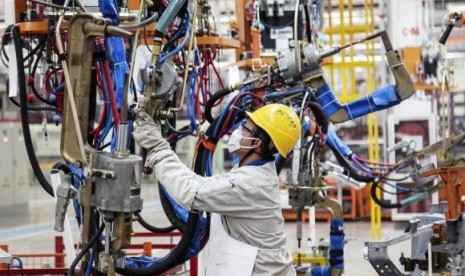 An employee works at the production line of an automobile factory in Dalian, Liaoning province, October 18, 2014.