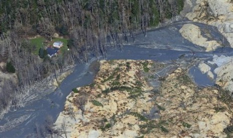 An intact house sits at left at the edge of the massive mudslide that killed at least eight people and left dozens missing is shown in this aerial photo, Monday, March 24, 2014, near Arlington, Wash. 