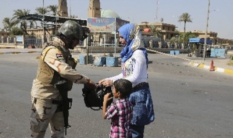 An Iraqi Army soldier searches a woman's bag amid tight security during Eid al-Adha celebrations in Baghdad, Iraq, Monday, Oct. 6, 2014. Eid al-Adha, or Feast of Sacrifice, commemorates what Muslims believe was Prophet Abraham's willingness to sacrifice hi