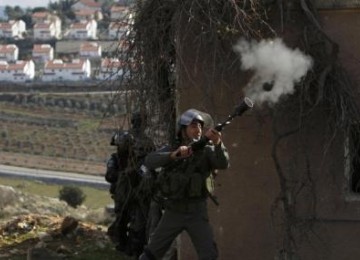 An Israeli border police officer fires a tear gas canister towards stone-throwing Palestinian demonstrators during clashes at a weekly protest against the nearby Jewish settlement of Halamish, West Bank.