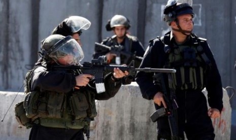  An Israeli border policeman aims his weapon towards Palestinian stone throwers during clashes following a protest against what organizers say are recent visits by Jewish activists to al-Aqsa mosque, at Qalandia checkpoint near the West Bank city of Ramall