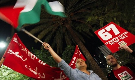 An Israeli man waves a Palestinian flag during a rally in Tel Aviv, supporting the Palestinian Authority's efforts to secure a diplomatic upgrade at the United Nations November 29, 2012. Some 300 Israelis took part in the rally on Thursday, several hours before the Palestinian Authority is expected to win an upgrade of its observer status at the United Nations from 