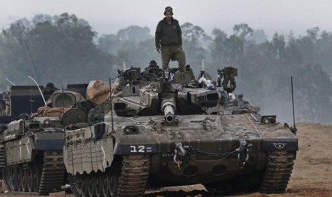 An Israeli soldier stands on a tank at a staging area near the Israel Gaza Strip Border, southern Israel, early Tuesday, Nov. 20, 2012. U.N. Secretary-General Ban Ki-moon is urging Israeli forces and Gaza militants to hold their fire, warning that a furthe