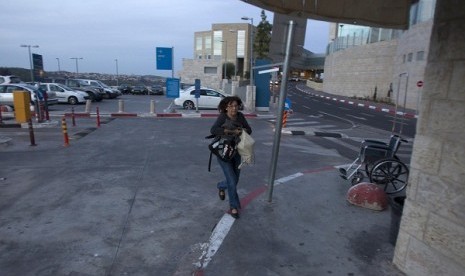 An Israeli woman runs to take cover as an air raid siren warns of incoming rockets at the parking lot of a hospital in Jerusalem November 16, 2012. 