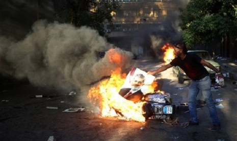 An opponent of ousted President Mohammed Morsi burns a poster of the former leader during clashes against Morsi supporters, in Cairo, Egypt, Monday, July 22, 2013. 