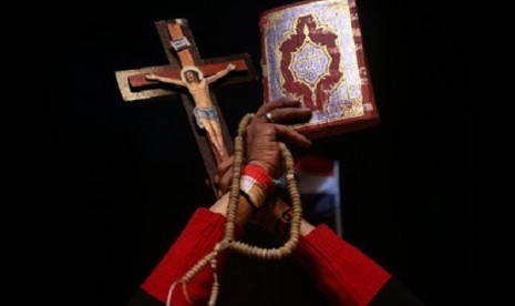 An opponent of ousted President Mohammed Morsi holds up Islam's holy book Quran (right) and Christian cross to show unity during a rally at Tahrir square, in Cairo, Egypt, late Friday, July 19, 2013. 