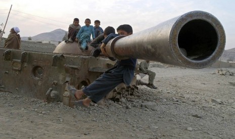 Anak-anak Afghanistan bermain di bangkai tank Soviet di distrik Behsood Jalalabad, Afghanistan, Senin (18/2). (AP/Rahmat Gul)