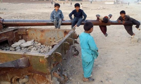 Anak-anak Afghanistan bermain di bangkai tank Soviet di distrik Behsood Jalalabad, Afghanistan, Senin (18/2). (AP/Rahmat Gul)