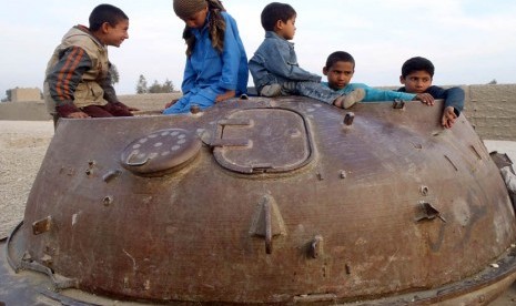 Anak-anak Afghanistan bermain di bangkai tank Soviet di distrik Behsood Jalalabad, Afghanistan, Senin (18/2). (AP/Rahmat Gul)