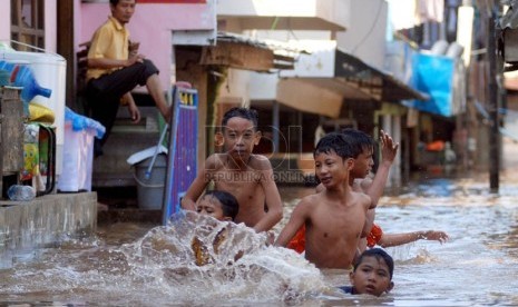  Anak-anak bermain dalam genangan air banjir di Kawasan Jatinegara,Jakarta Timur,Rabu (13/2). (Republika/Prayogi)