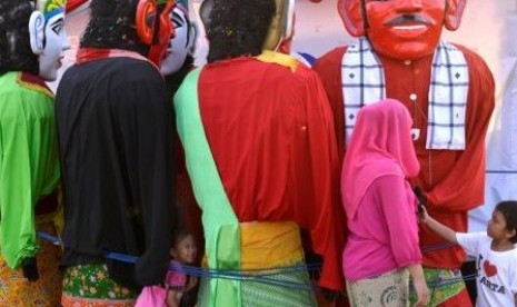 Anak-anak bermain dengan Ondel-ondel yang tak digunakan saat Lebaran Betawi di Silang Monas, Jakarta Pusat