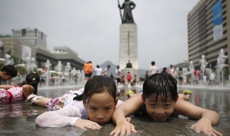 Anak-anak bermain di air terjun di tengah udara musim panas di Gwanghwamun, Seoul, Juli 2014. Total populasi Korea Selatan diperkirakan akan turun dari 51,75 juta pada 2024 